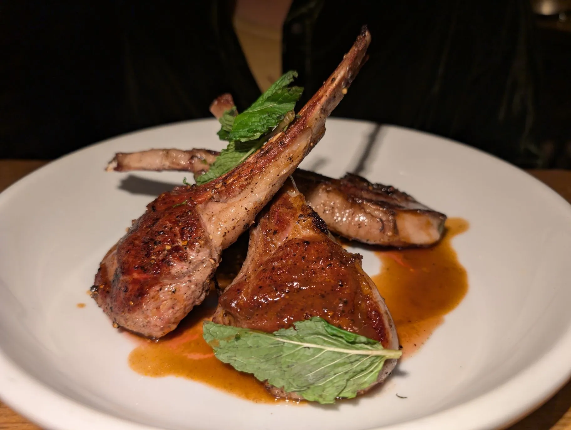 Seared lamb chops plated with fresh mint and pan sauce